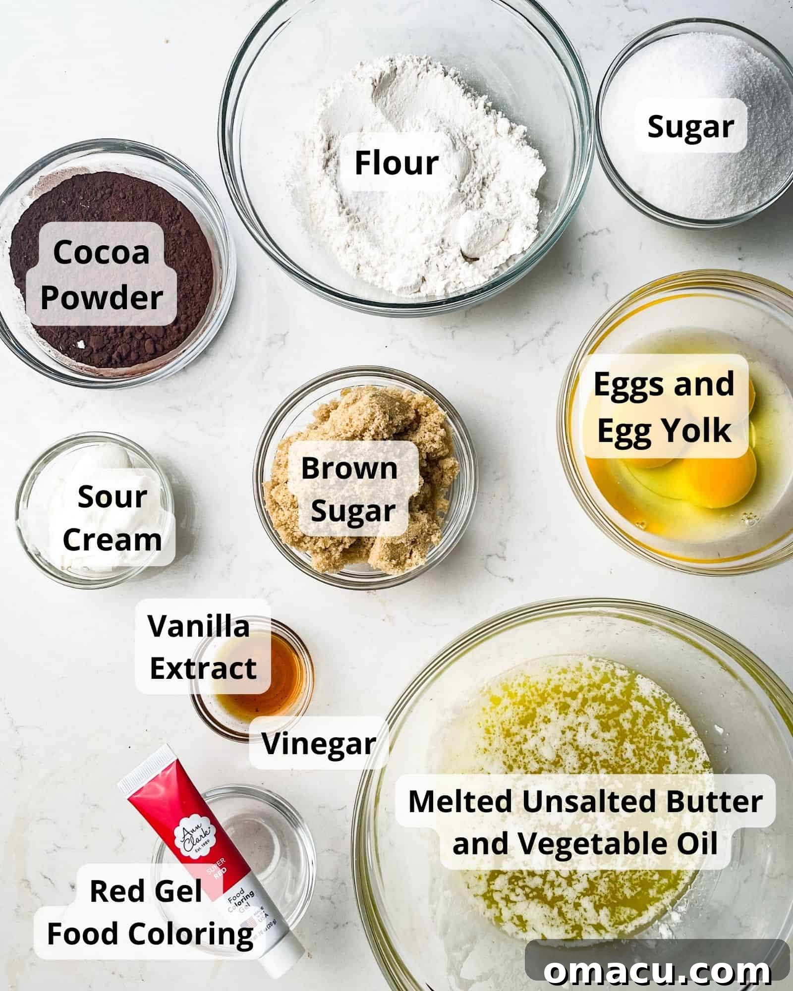 A beautifully arranged selection of fresh ingredients for red velvet brownies, including flour, sugars, eggs, butter, oil, cocoa, salt, red food coloring, and sour cream, ready for baking.