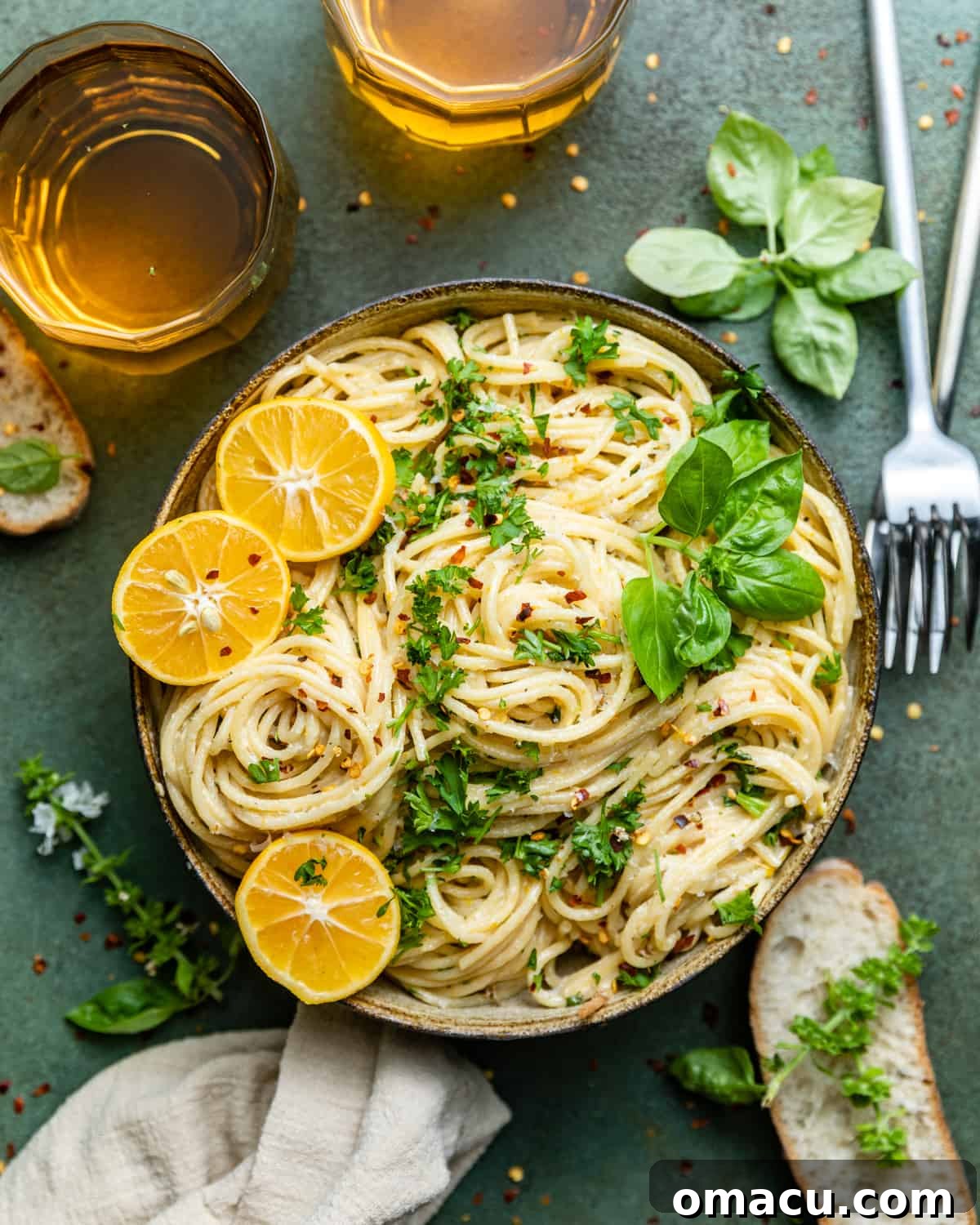 A vibrant bowl of lemon garlic pasta, garnished with fresh lemon slices, basil leaves, and chopped parsley, ready to be served.