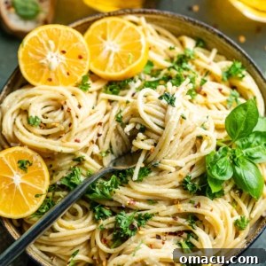A bowl of lemon garlic pasta with a fork, garnished with sliced lemons and fresh herbs, highlighting its appeal.
