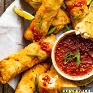 crab rangoon egg rolls in a basket with a bowl of sweet and sour dipping sauce.
