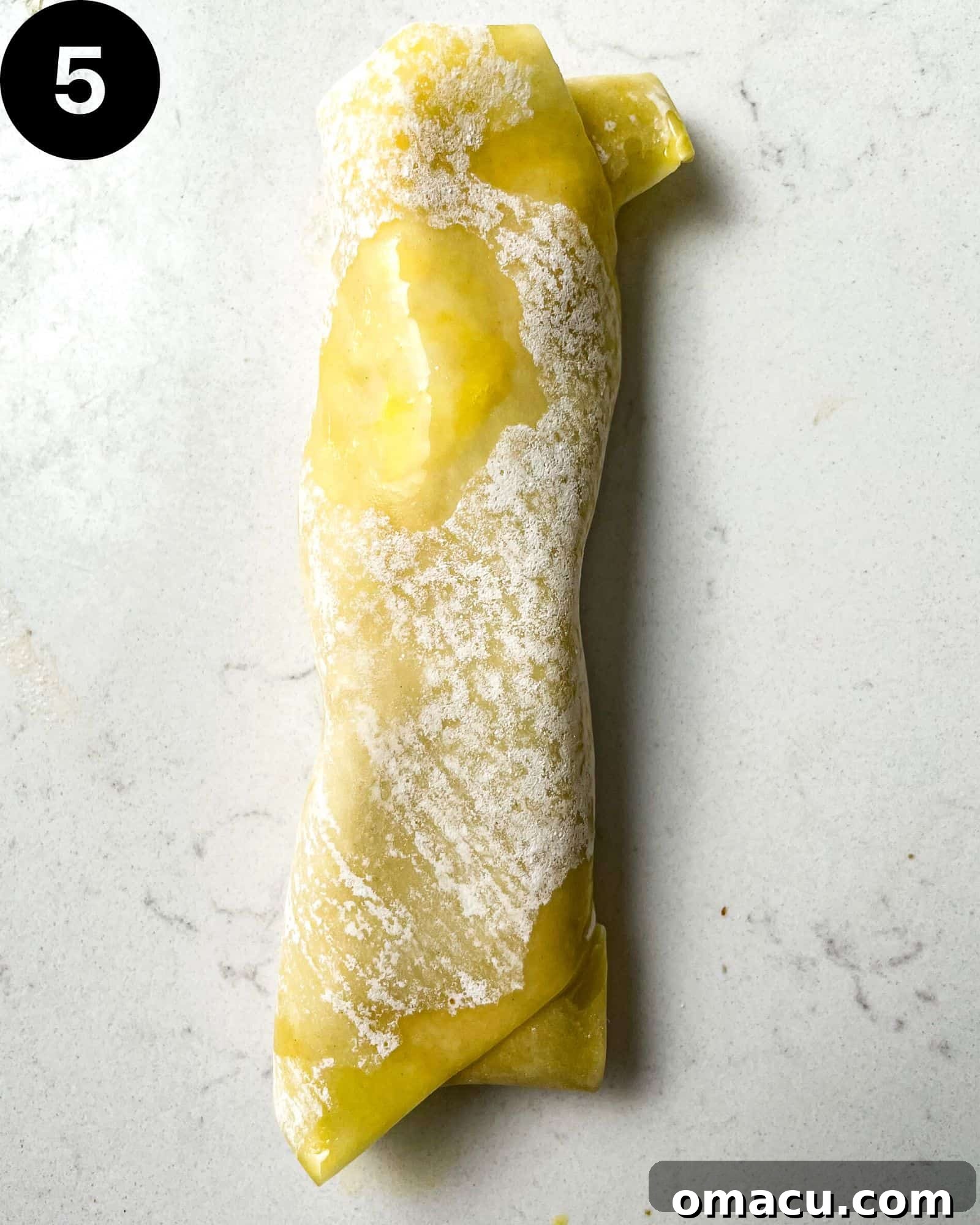 A perfectly wrapped crab rangoon egg roll, tightly sealed and ready for frying, showcasing the complete rolling technique.