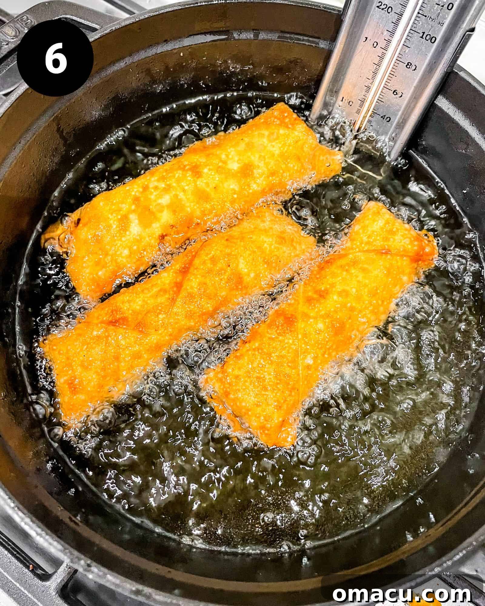Several egg rolls are submerged in hot, bubbling oil within a large pot, actively frying to a golden crisp perfection.
