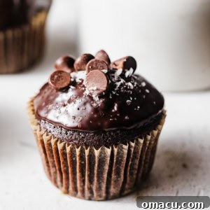 Triple Chocolate Muffins, freshly baked and topped with ganache, on a white surface.