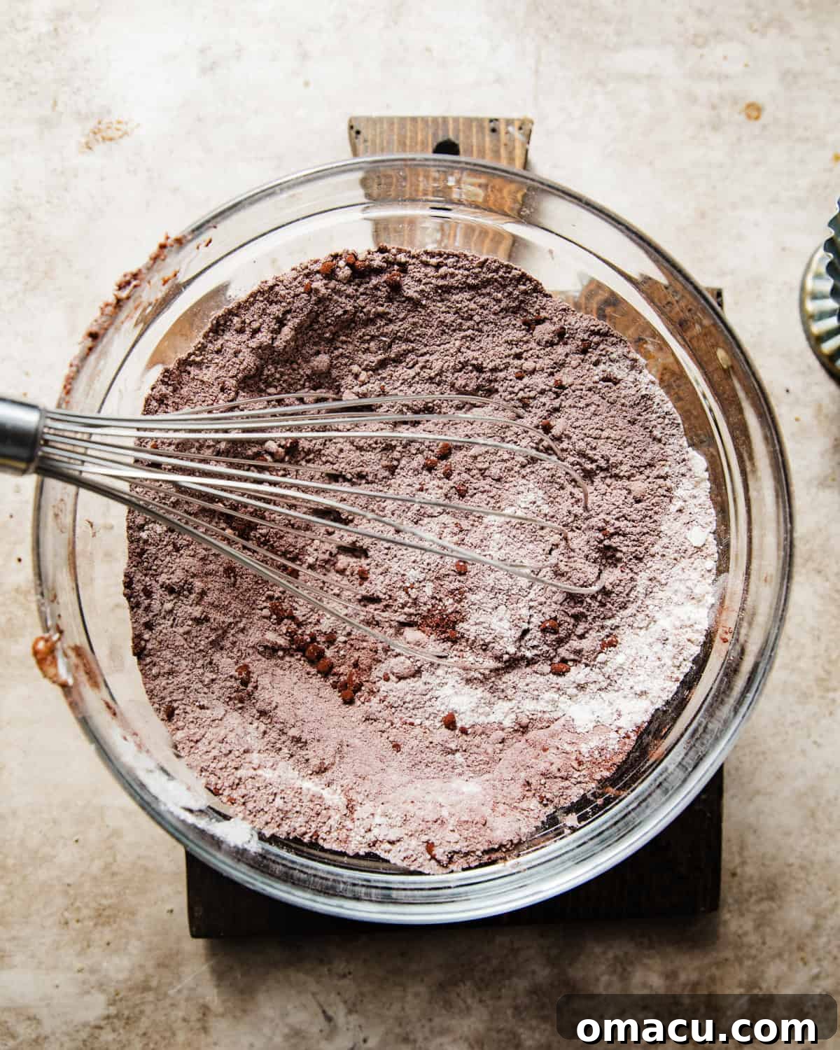 Dry ingredients, including flour, cocoa powder, and sugar, are whisked together in a large mixing bowl, ready for the next step of the recipe.