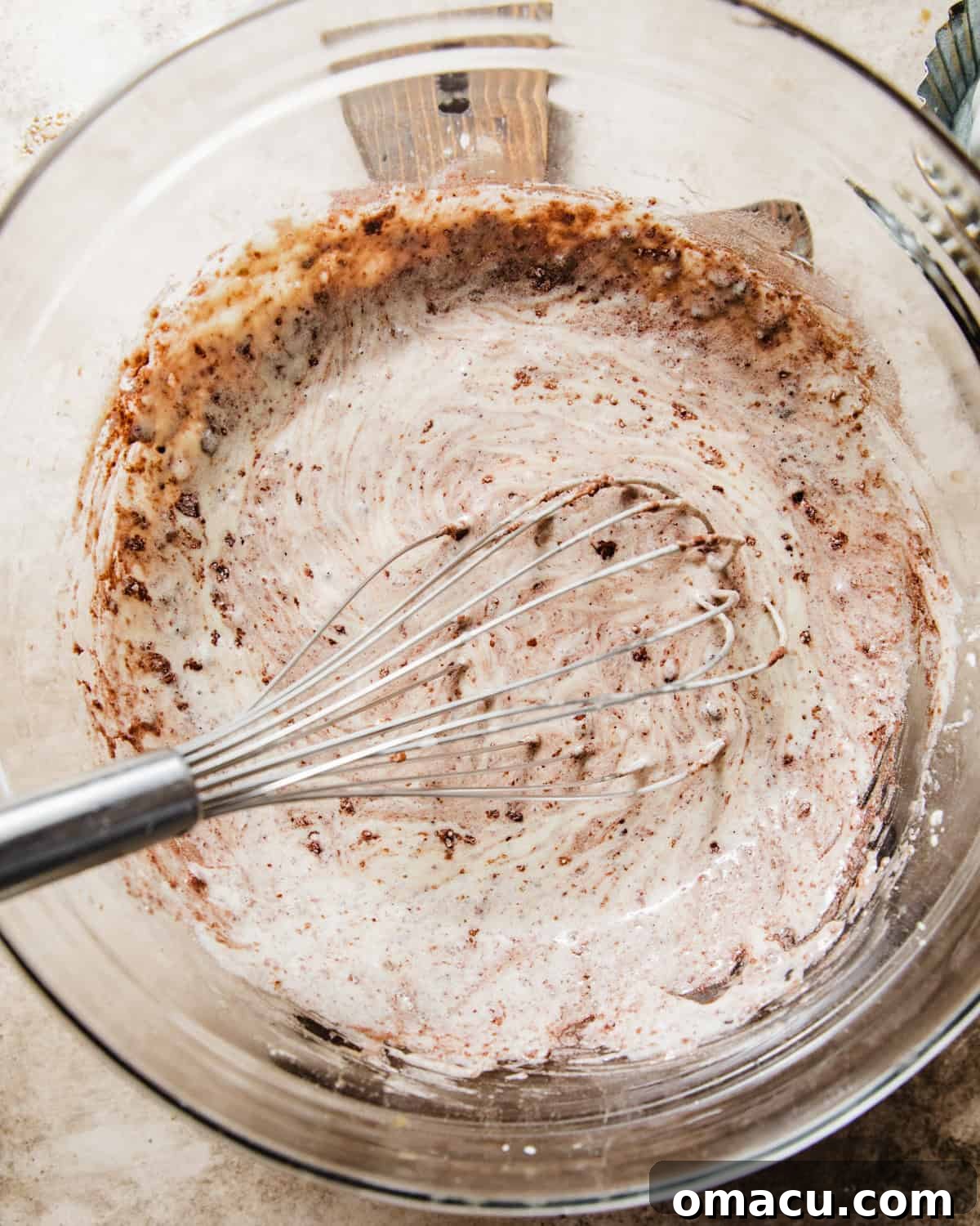 The chocolate muffin batter is beginning to come together in a bowl as half of the dry ingredients are gently mixed into the wet ingredients.