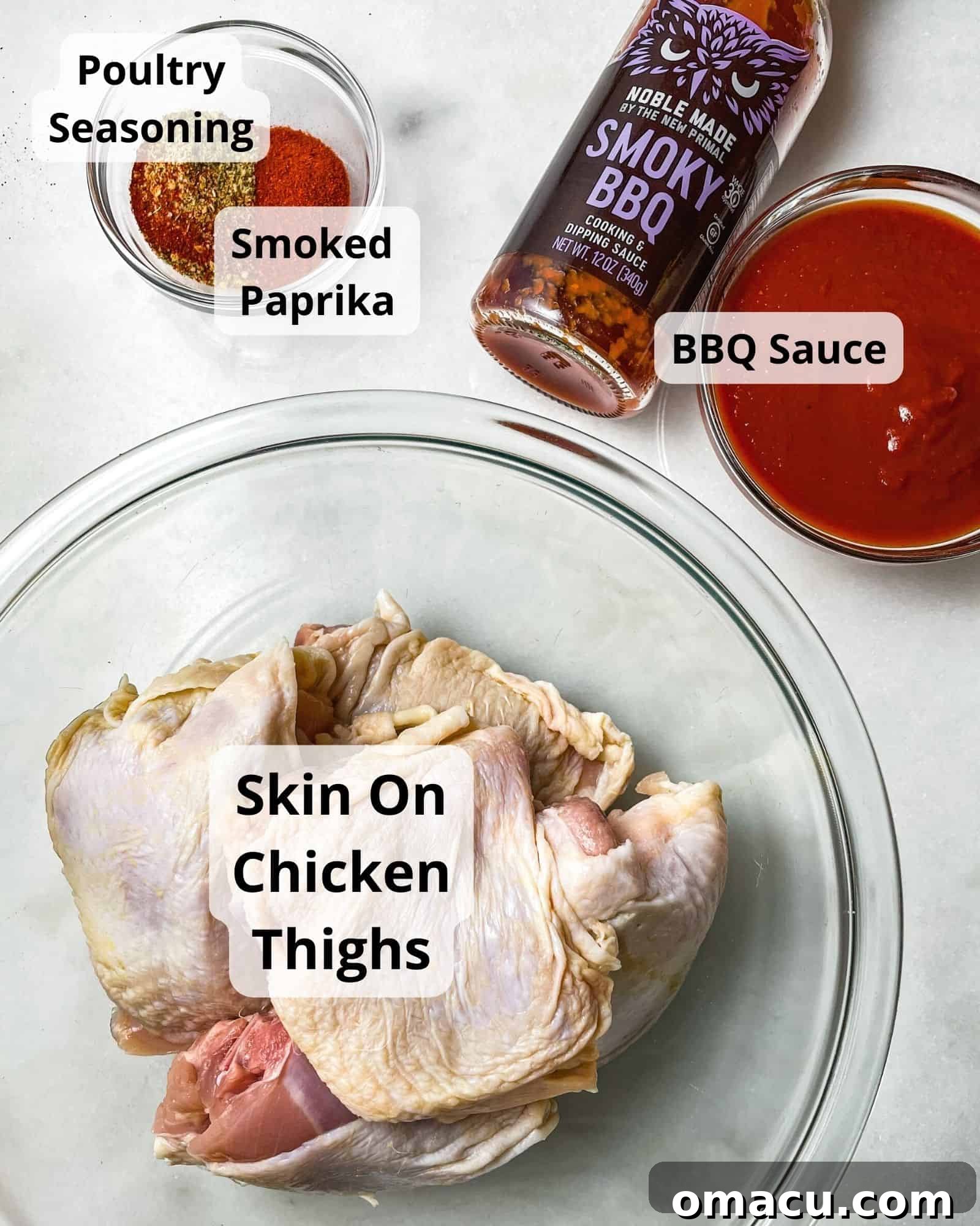 Ingredients laid out for baked bbq chicken thighs: raw chicken thighs, a bottle of bbq sauce, a bowl of poultry seasoning, and a small dish of smoked paprika.