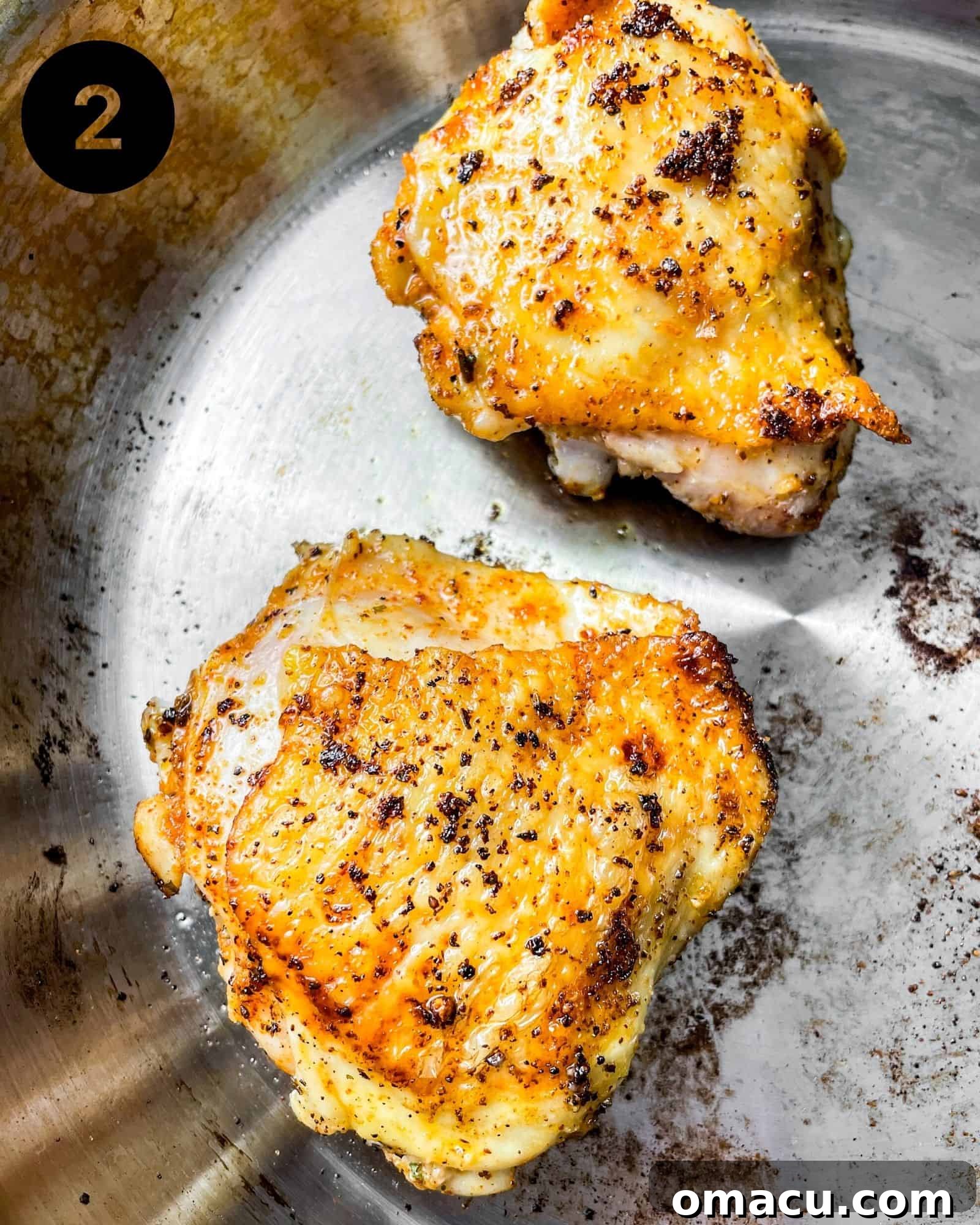 Close-up of chicken thighs searing in a hot skillet, with golden-brown, crispy skin visible on one side.