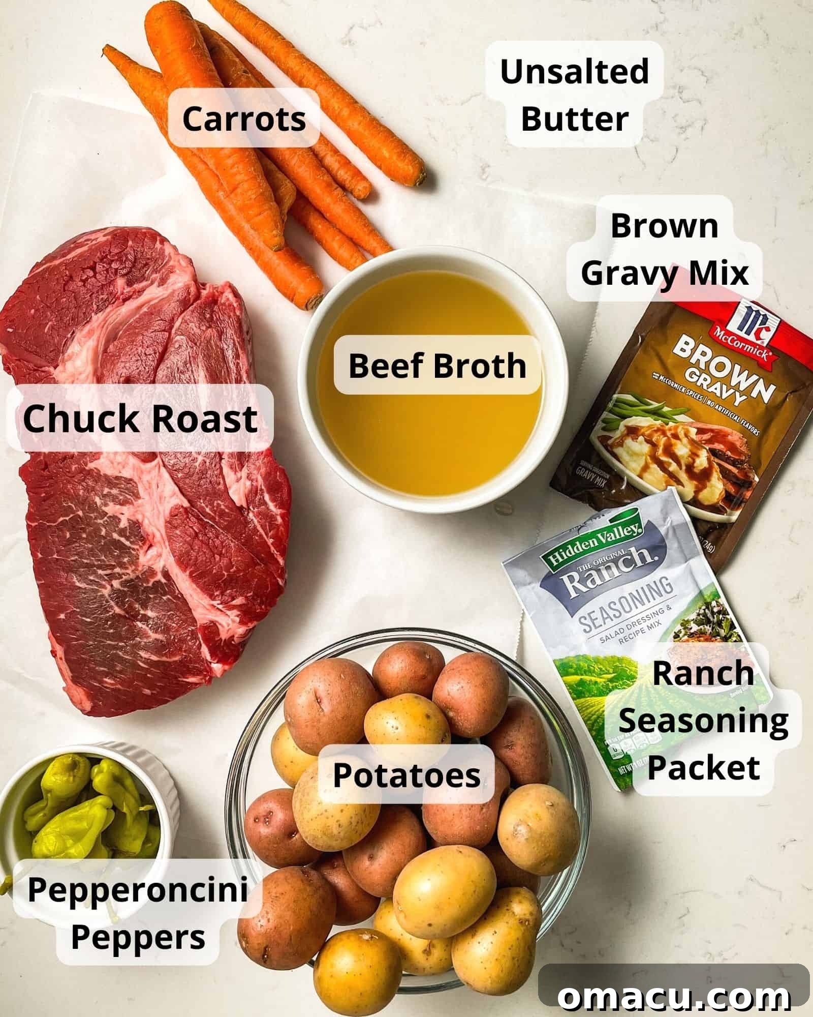 ingredients to make mississippi pot roast - chuck roast, beef broth, carrots, butter, brown gravy mix, ranch mix, pepperoncini peppers, and potatoes.