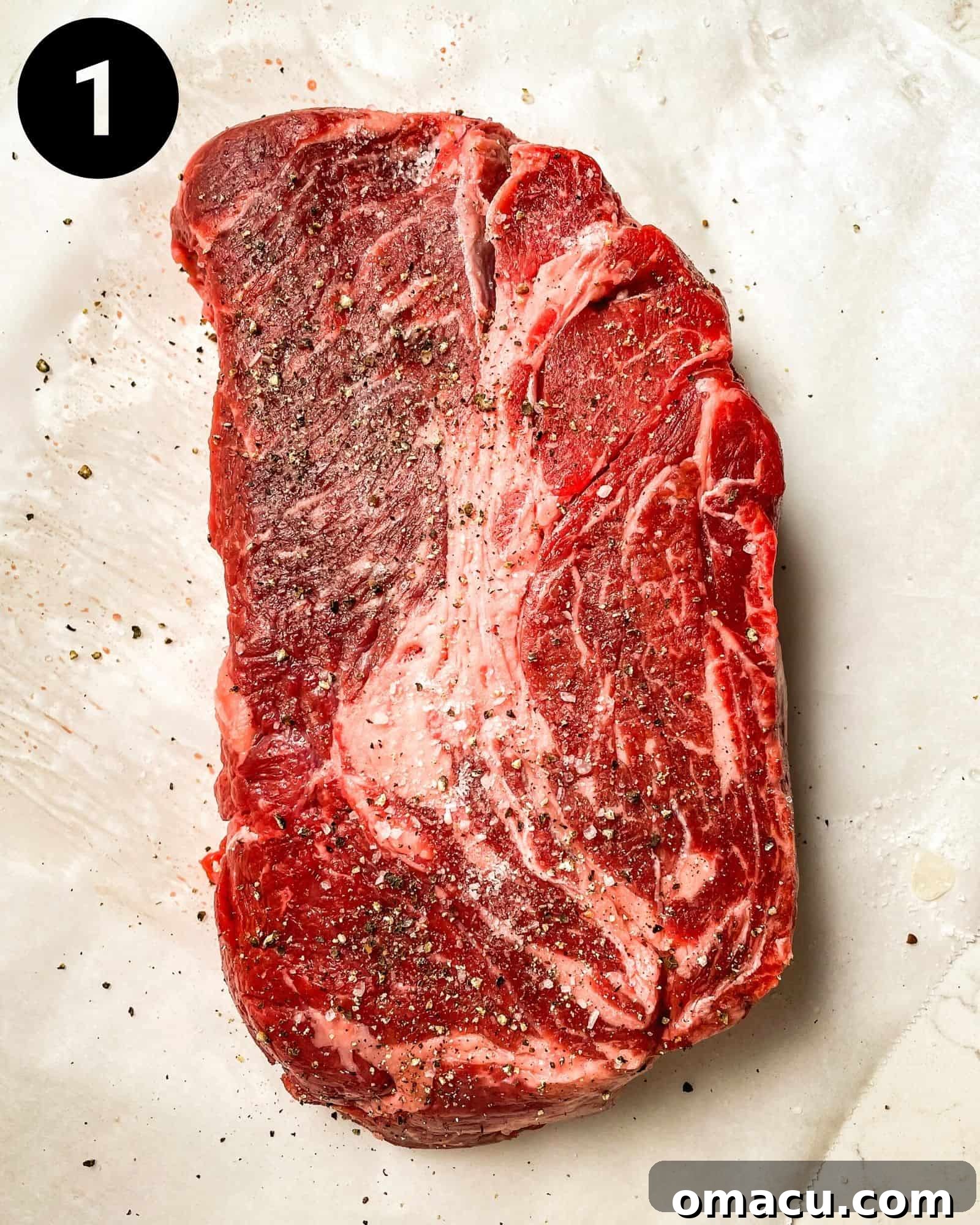 a chuck roast on a piece of parchment paper seasoned with salt and pepper.