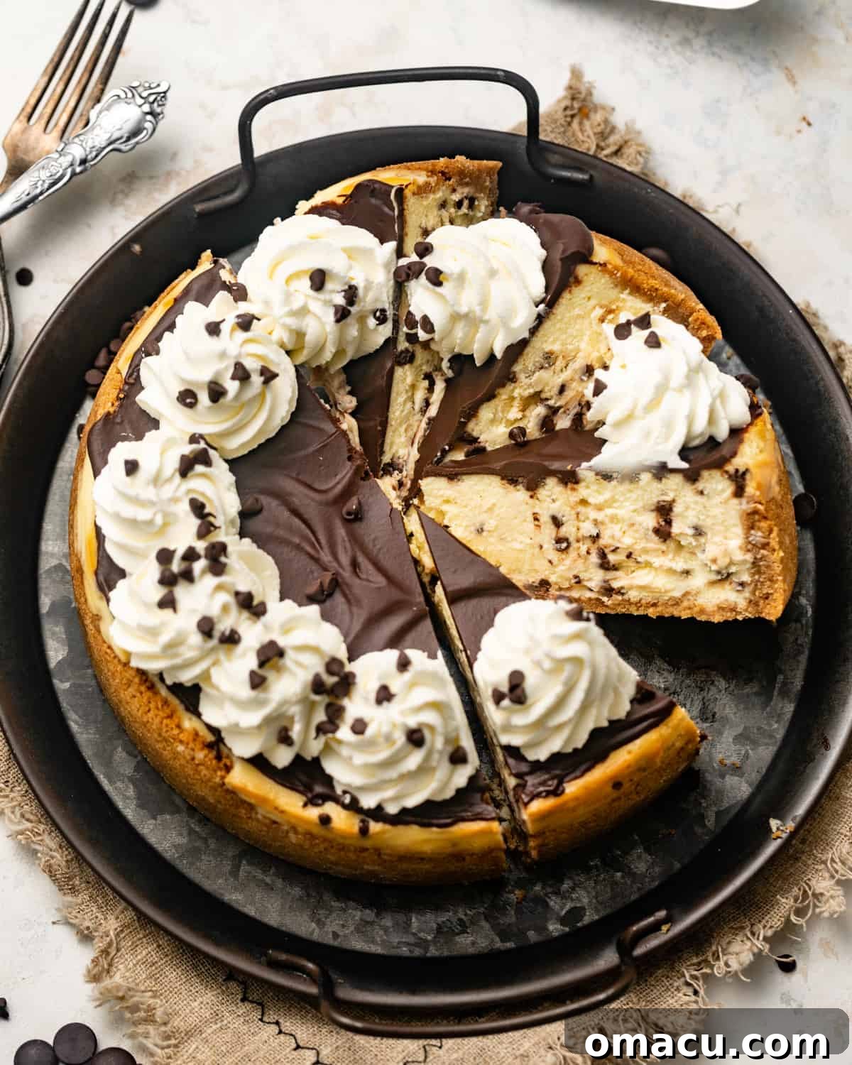 A beautifully presented chocolate chip cheesecake on a black serving tray, with several slices already cut out, revealing its rich interior.