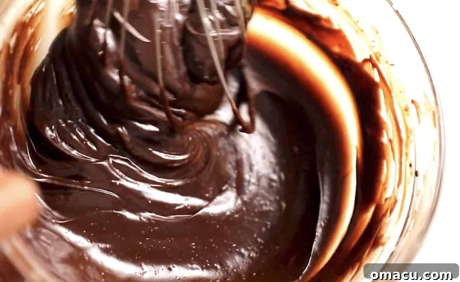 Smooth and rich chocolate ganache in a bowl, perfectly prepared to be poured over the chilled cheesecake.