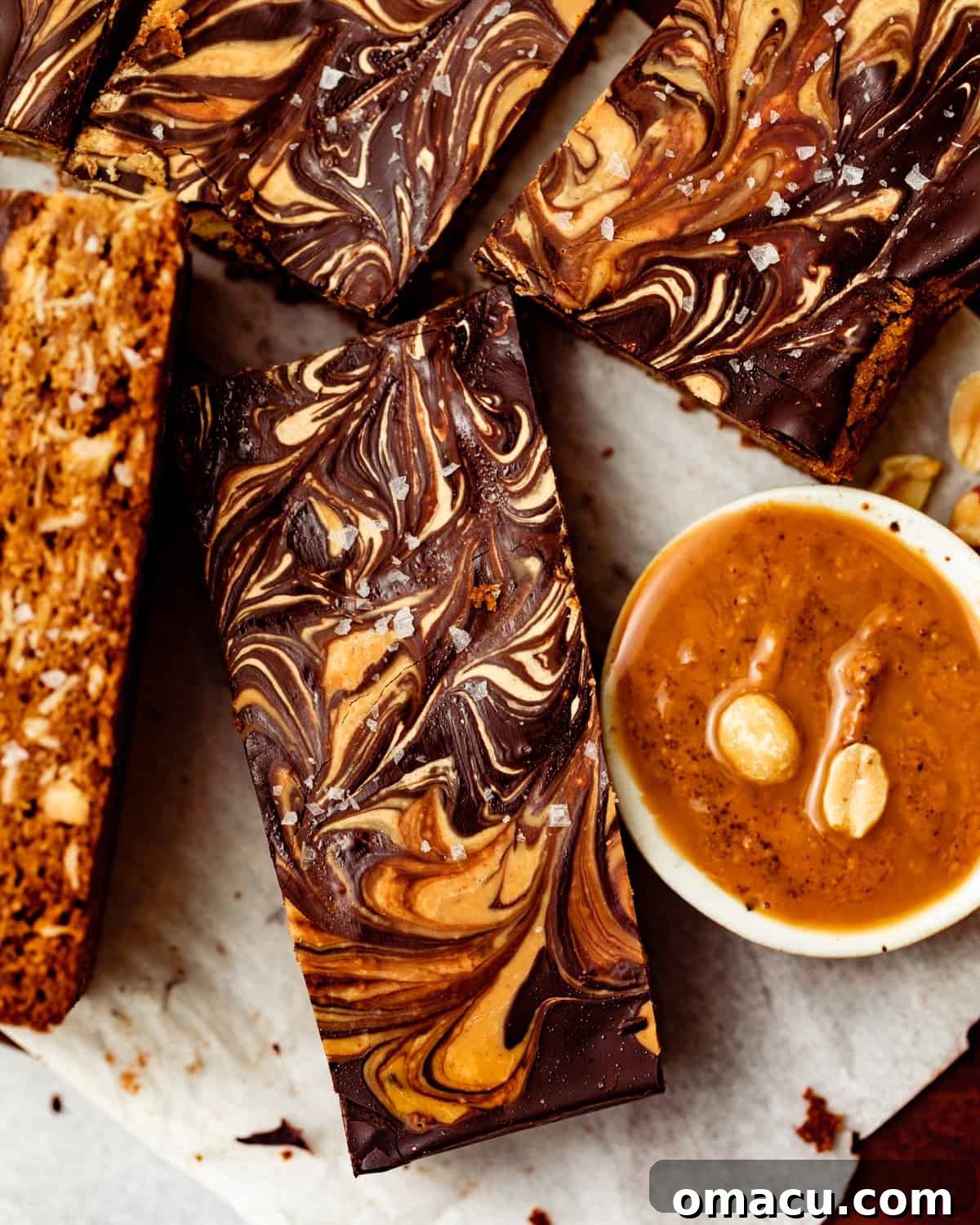 A close-up photo showcasing the rich, melted chocolate and peanut butter swirl on top of an oatmeal bar, with a bowl of creamy peanut butter in the background.