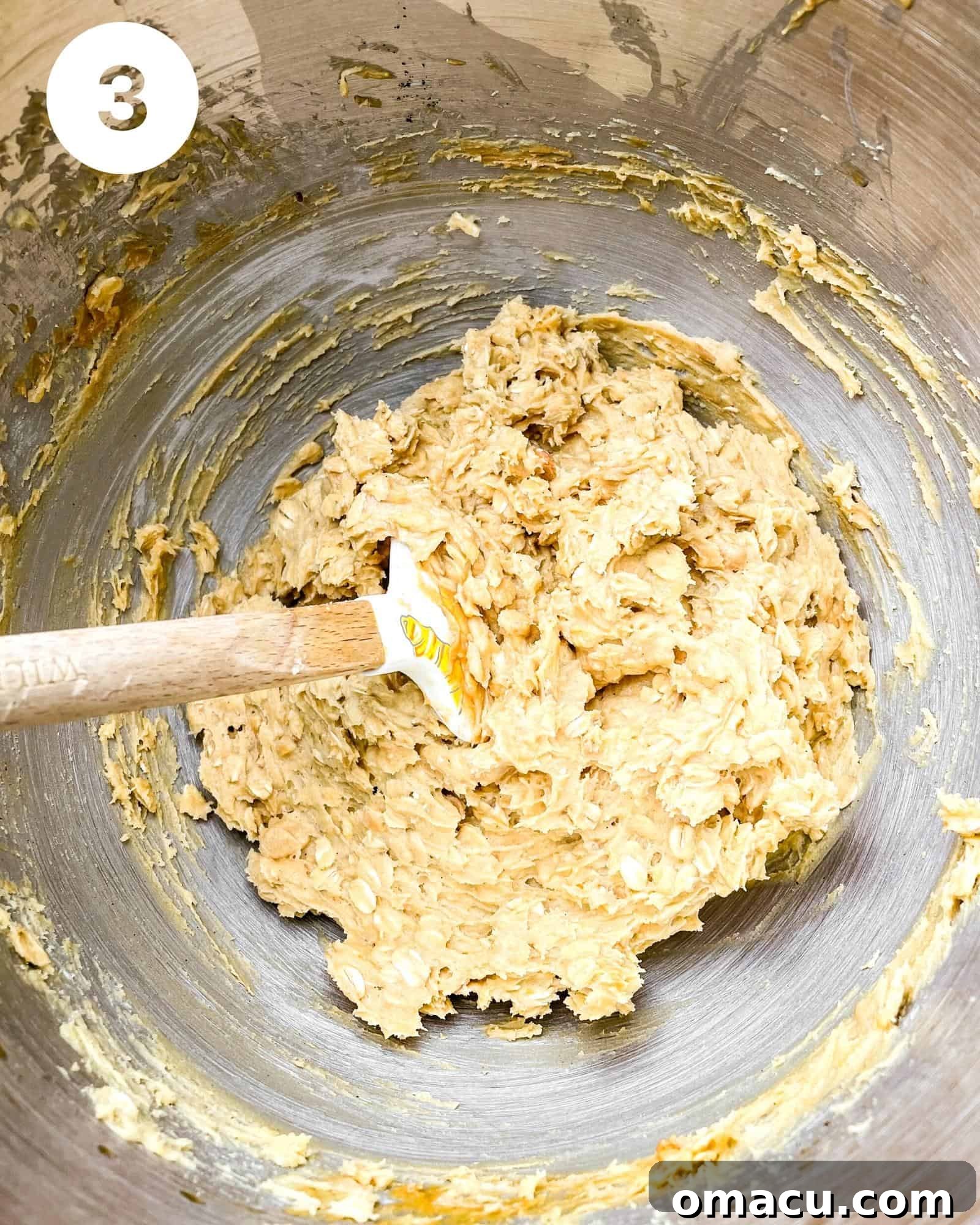 The wet and dry ingredients for the oatmeal bar base have just been combined in a large mixing bowl, forming a thick, uniform dough.