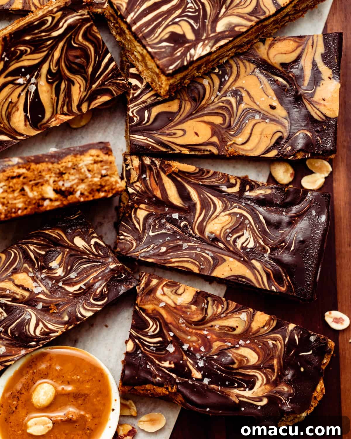 A collection of chocolate peanut butter oatmeal bars, perfectly cut into squares, are neatly lined up and presented on a rustic brown plate.