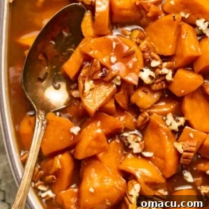 A casserole dish filled with golden candied sweet potatoes, featuring a serving spoon ready to dish out this festive side.