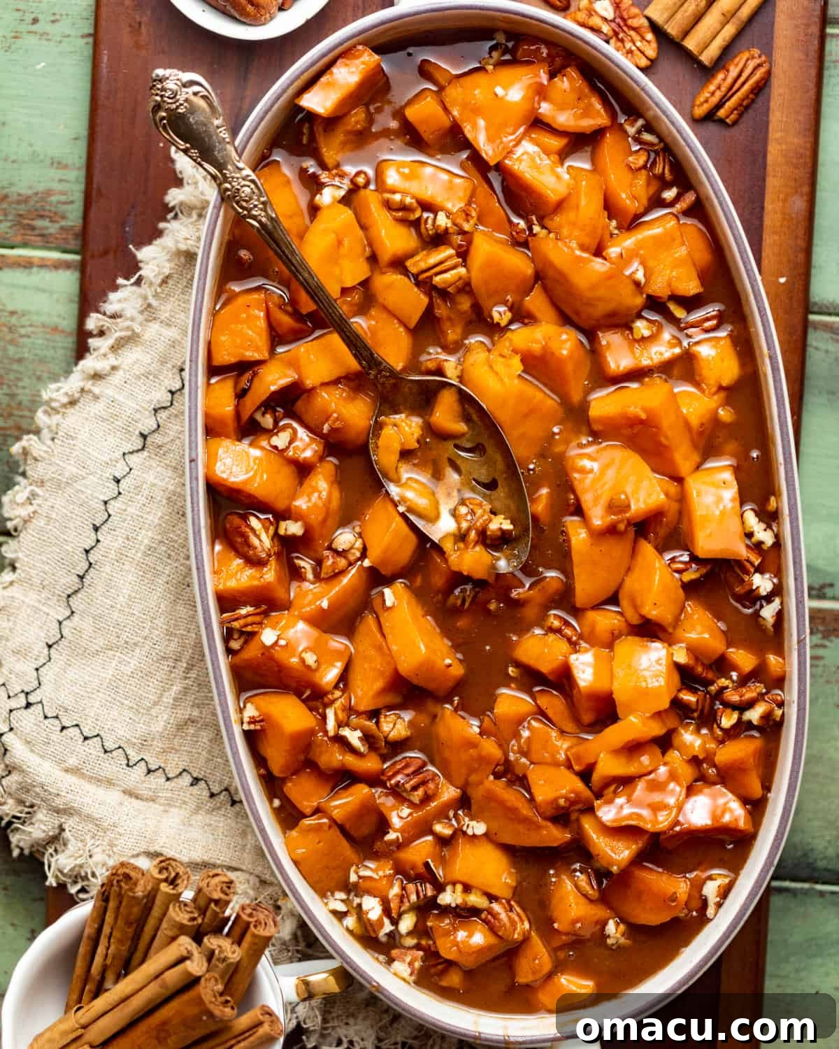 A close-up shot of a casserole dish brimming with perfectly cooked, glazed candied sweet potatoes.