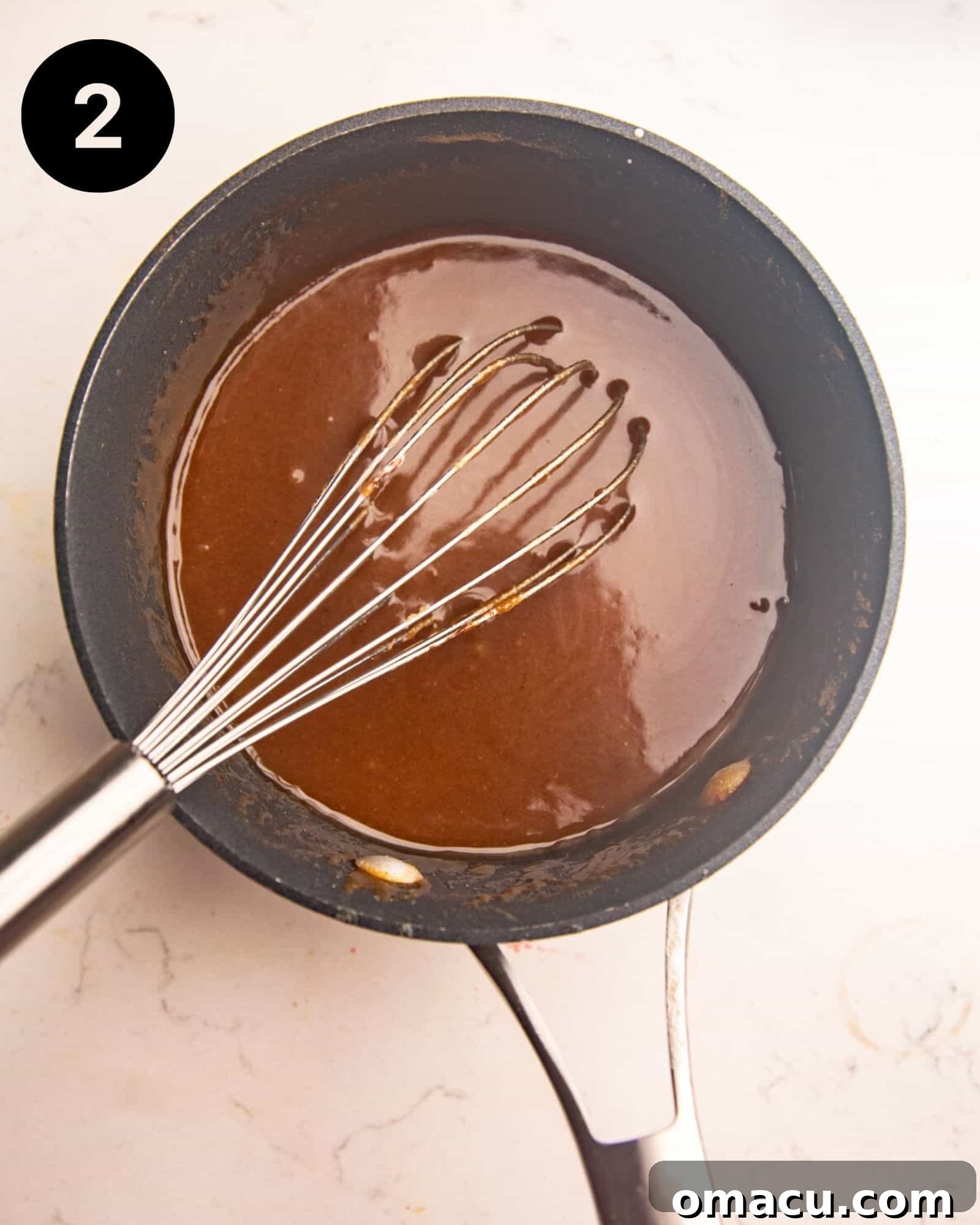 A medium saucepan containing a simmering, rich, buttery brown sugar syrup, glistening and ready to be poured.