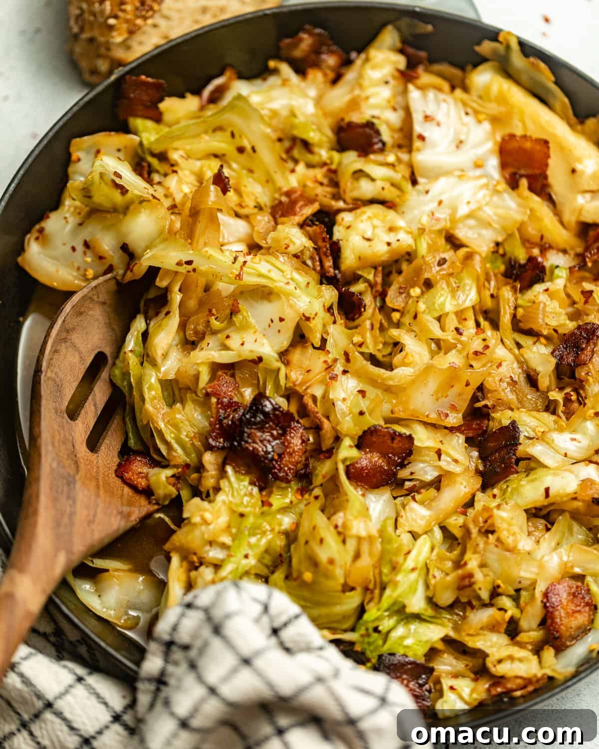 fried cabbage in a pan topped with bacon.