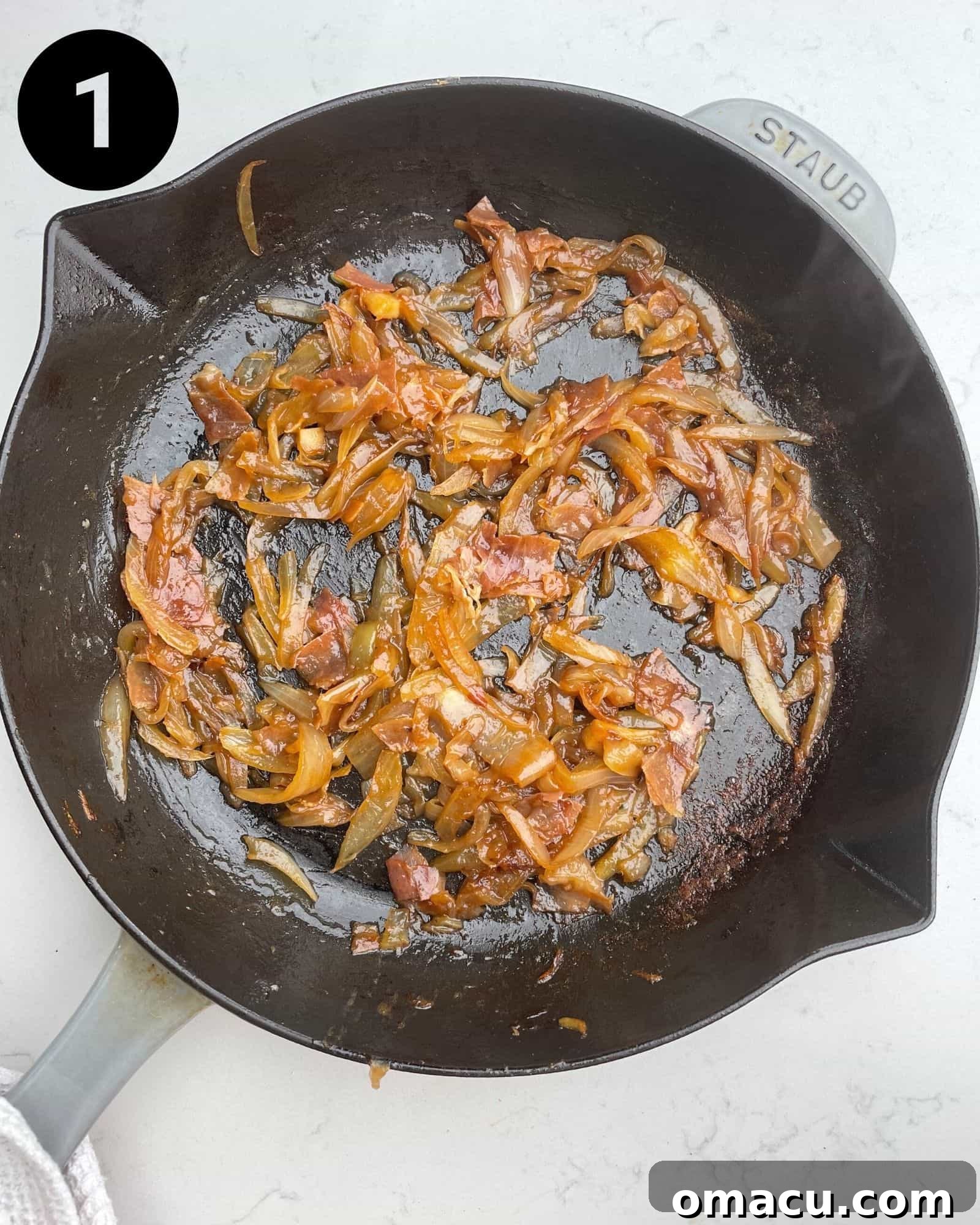 Close-up of perfectly caramelized onions simmering in a skillet, their color a rich golden-brown.