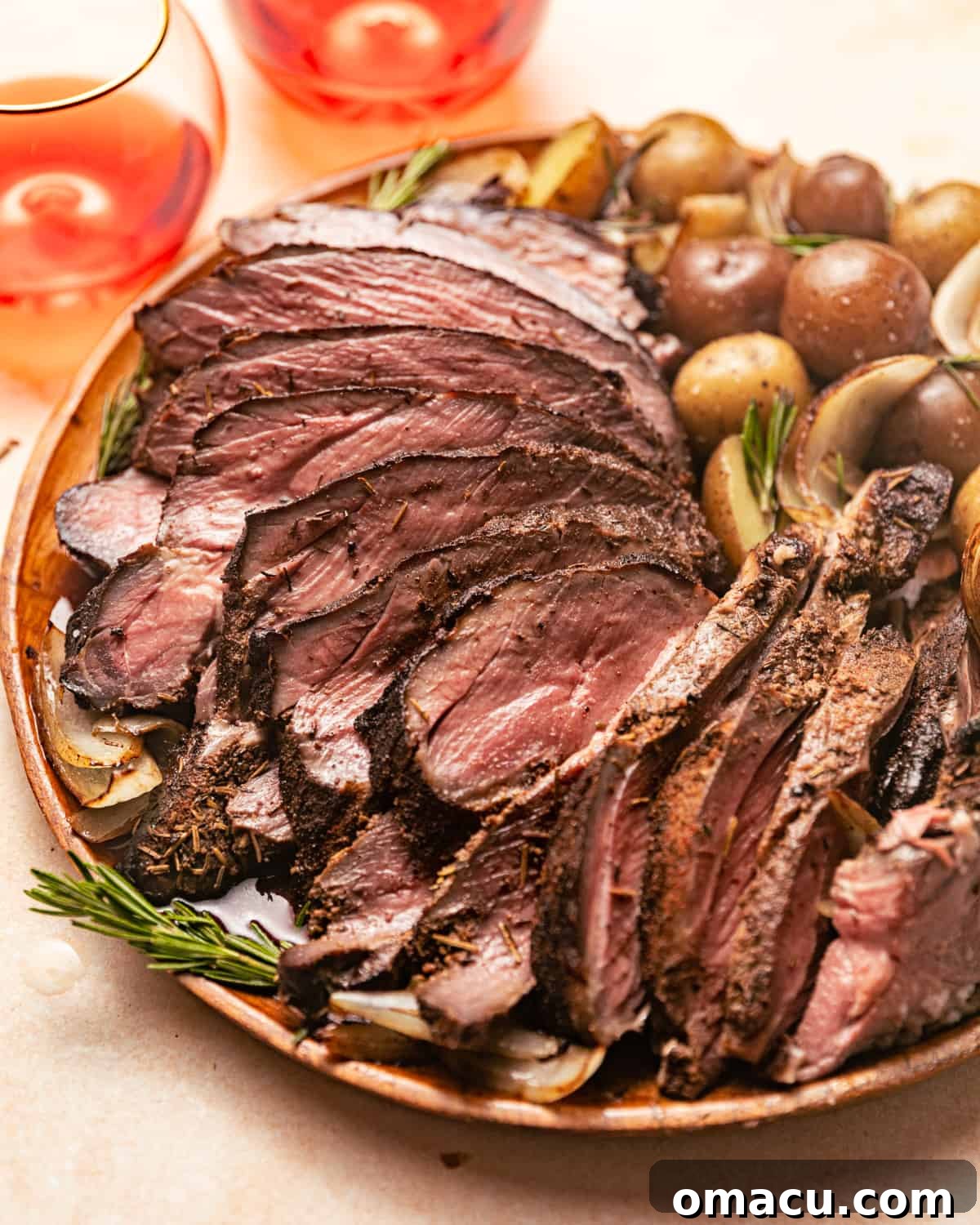 Carved smoked leg of lamb garnished with fresh rosemary sprigs on a rustic wooden board.