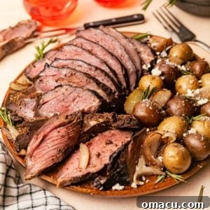 smoked leg of lamb on a plate in front of two wine glasses and a carving fork.