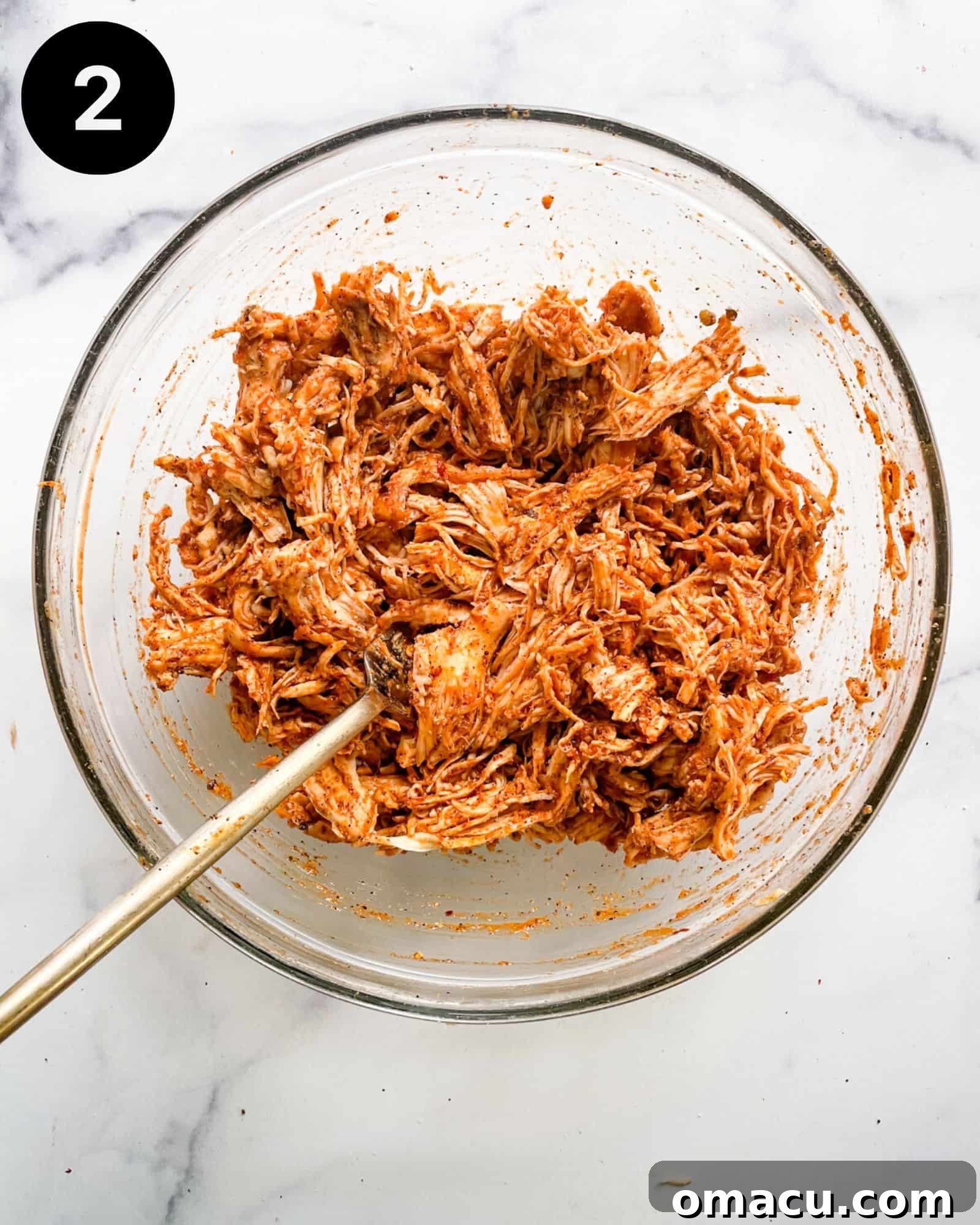 A bowl of perfectly shredded chicken mixed with rich taco sauce and savory taco seasoning, creating a delectable filling for the tacos.