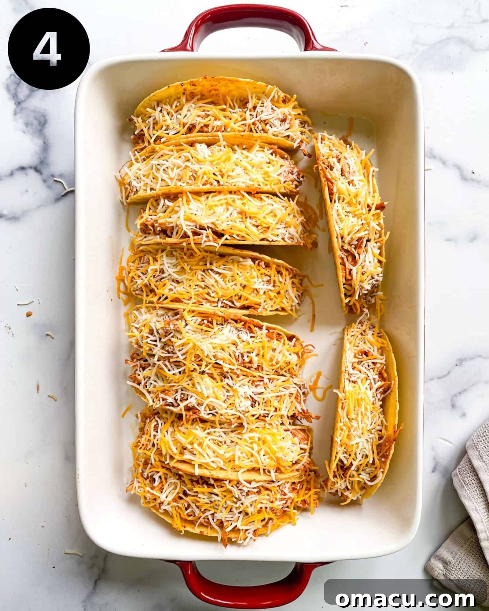 A baking pan filled with freshly baked chicken tacos, showing the cheese perfectly melted and bubbling, and the shells golden brown, straight out of the oven.