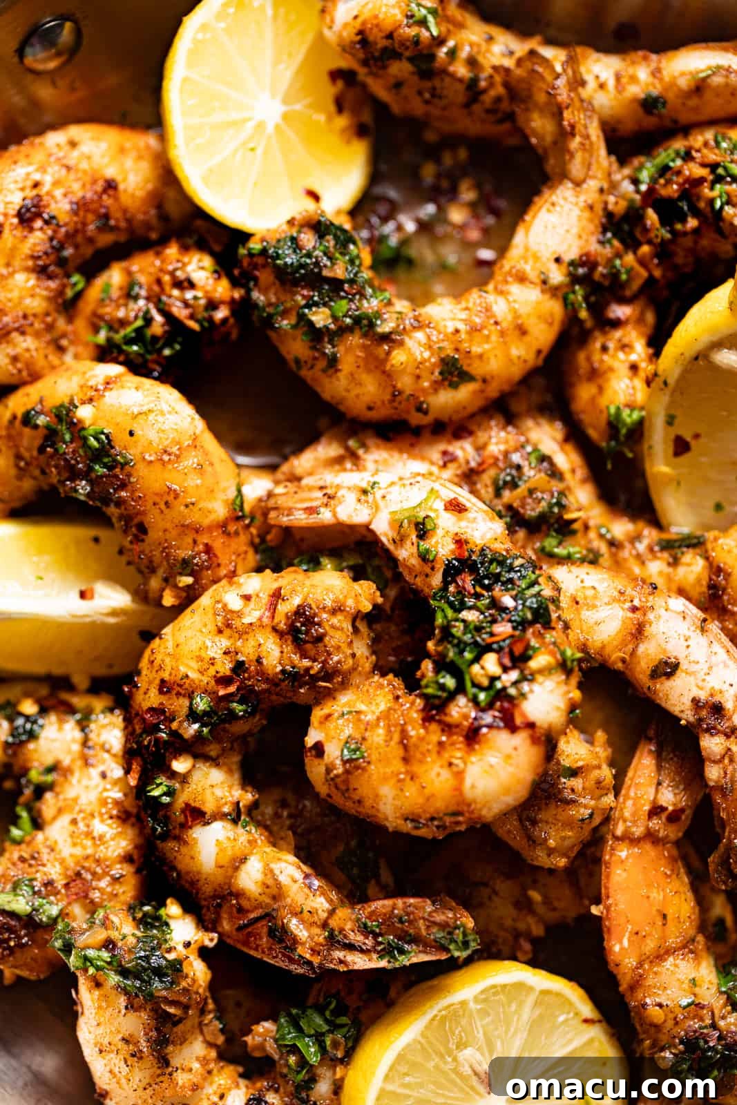 Close-up photo of perfectly pan-seared jumbo shrimp displaying a beautiful golden-brown crust and a vibrant pink hue, nestled in a cast iron skillet.