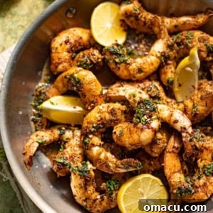 Golden pan-seared shrimp in a skillet with fresh lemons and parsley, highlighting the dish's vibrant appearance.