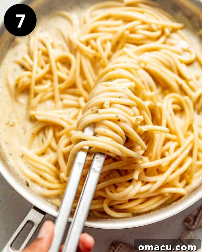 Pasta being tossed in the creamy white wine sauce.