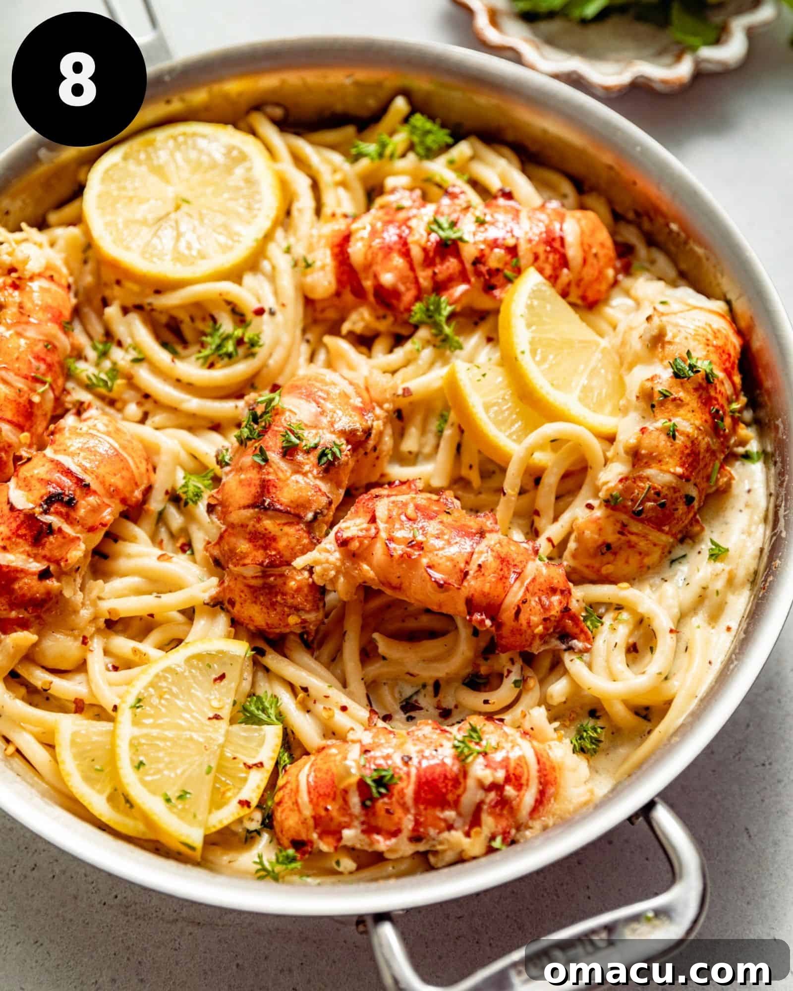 butter poached lobster in a skillet on top of pasta.
