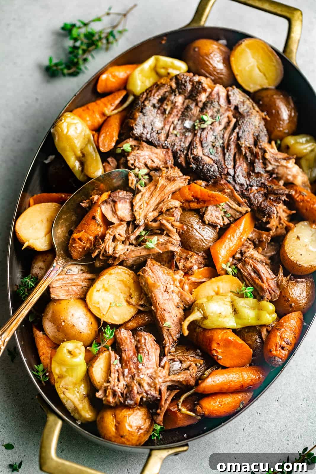 A succulent Mississippi pot roast served in a festive dish, garnished with fresh thyme and vibrant pepperoncini peppers, ready to be enjoyed as a centerpiece for an Easter meal.