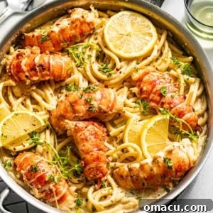 Luxurious butter-poached lobster tails elegantly served over a bed of pasta in a pan, garnished with vibrant lemons and fresh parsley.