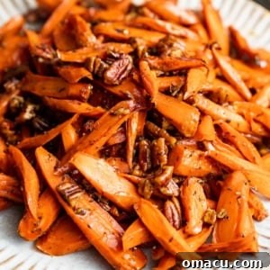 A serving of glistening brown sugar honey glazed carrots on a white plate, showcasing their rich color and inviting glaze.