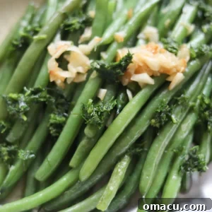 Vibrant green beans, specifically haricots verts, artfully arranged on a pristine white plate and garnished with crunchy slivered almonds.