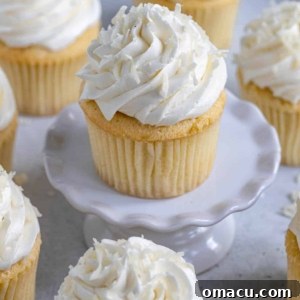 Delicate coconut cupcakes topped with fluffy frosting and generously sprinkled with toasted coconut flakes.