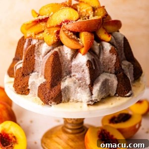 An elegant peach cobbler pound cake presented on a cake stand, beautifully topped with caramelized roasted peaches.