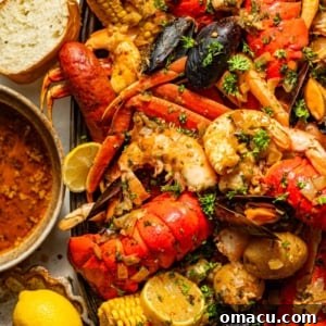 A festive Cajun seafood boil arranged on a large serving tray, accompanied by a bowl of rich garlic butter sauce, crusty bread, and fresh lemon slices.