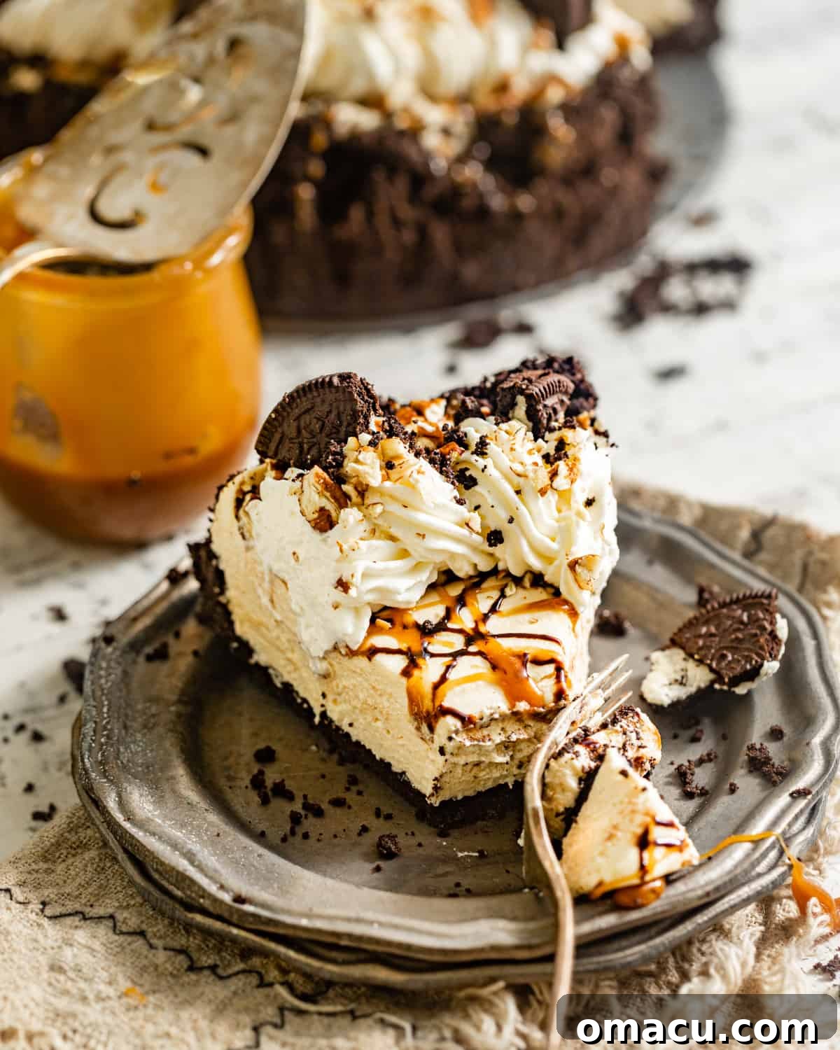 A delectable slice of turtle pie on a white plate, showing its creamy filling and chocolate crust, with a bite taken out.