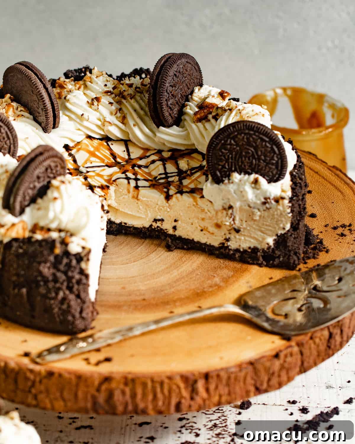 A whole turtle pie beautifully presented on a cake stand, garnished with whipped cream, chocolate, caramel, and pecans.