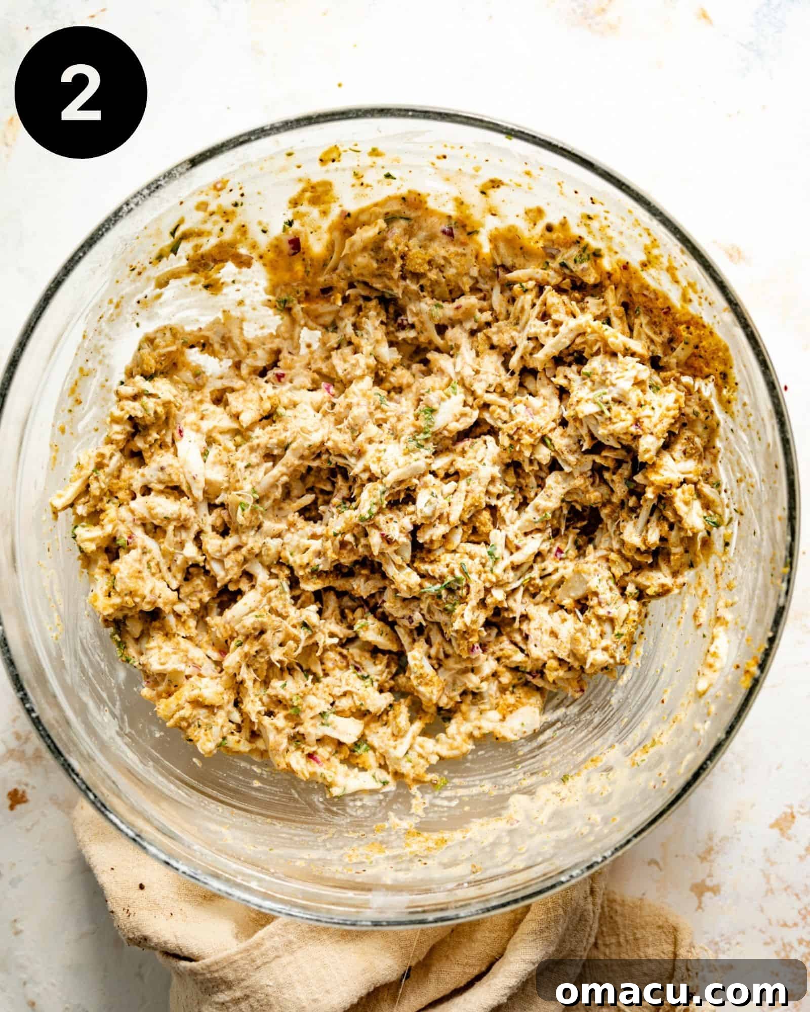 The best crab cake mixture, rich with lump crab meat and fresh herbs, ready for forming, in a large glass mixing bowl.