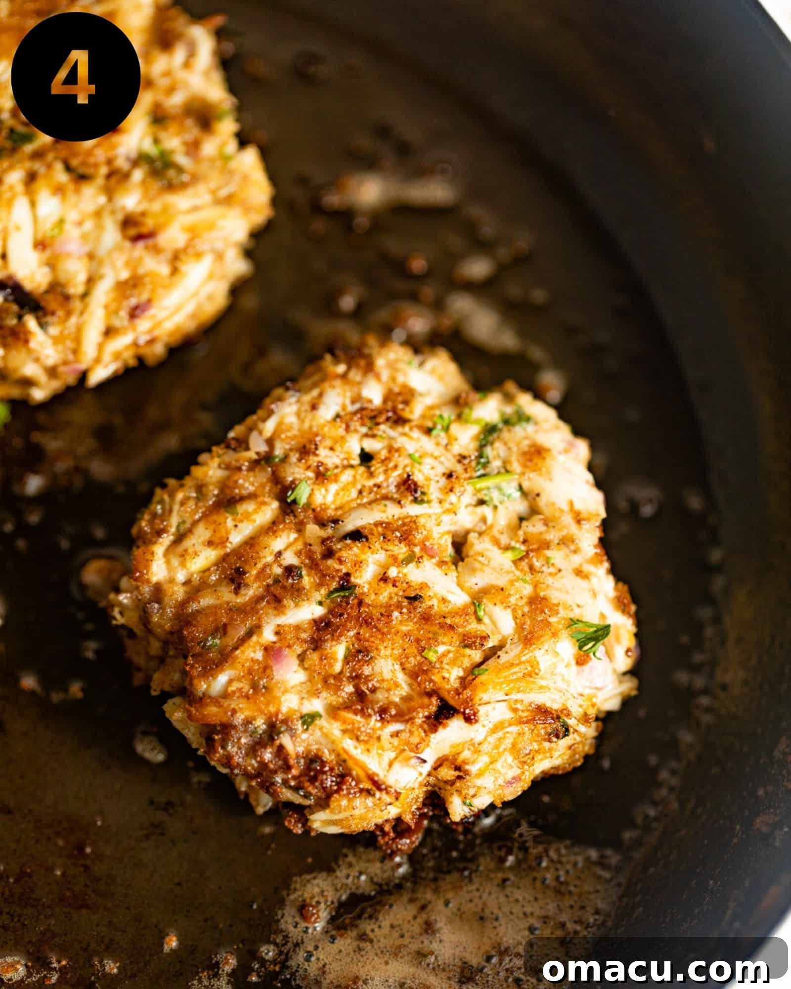 Perfectly pan fried crab cakes sizzling in a hot, oiled cast iron skillet, developing a golden crust.