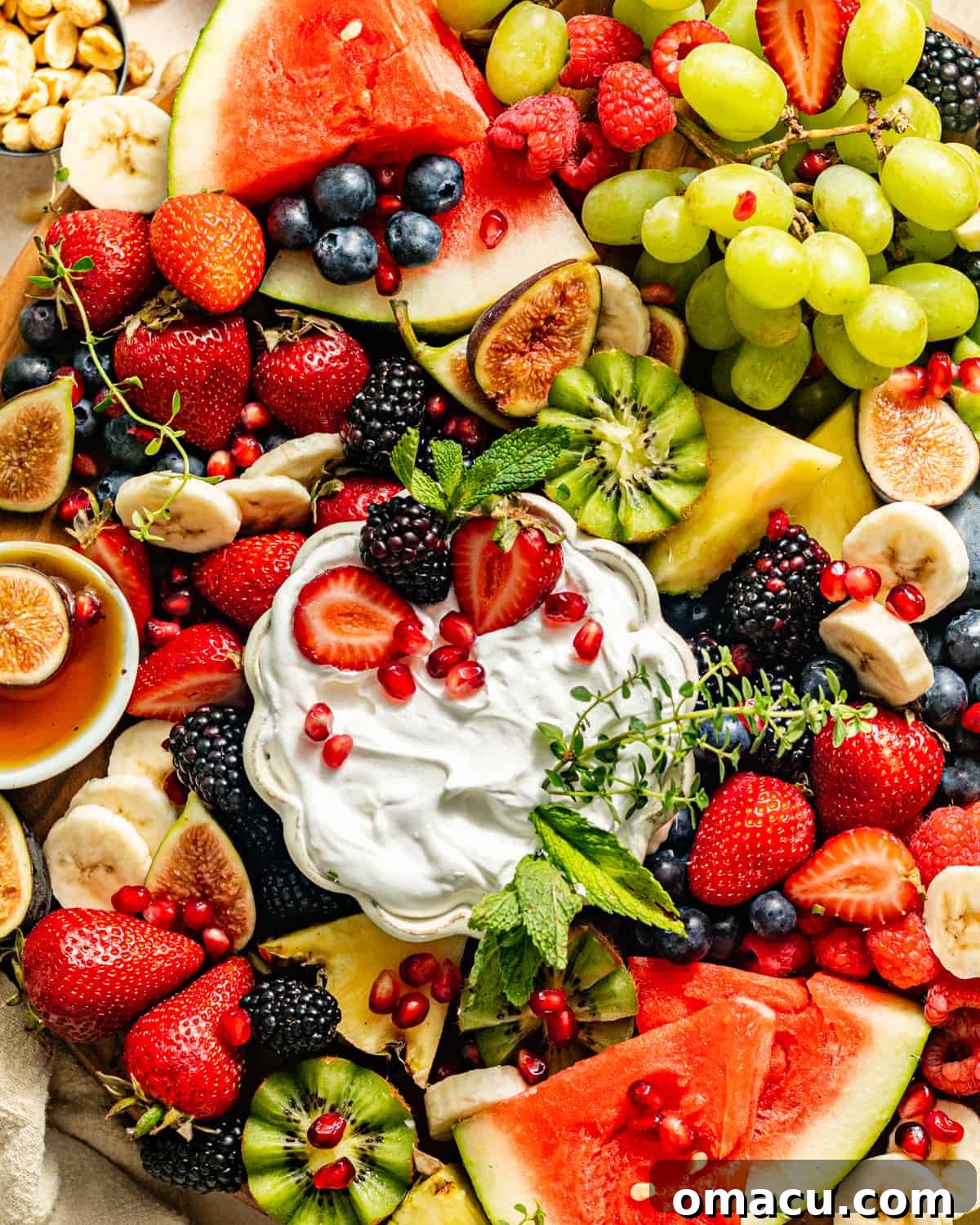 A selection of fresh fruits beautifully arranged on a fruit platter, accompanied by various dips in small bowls, ready for a party.