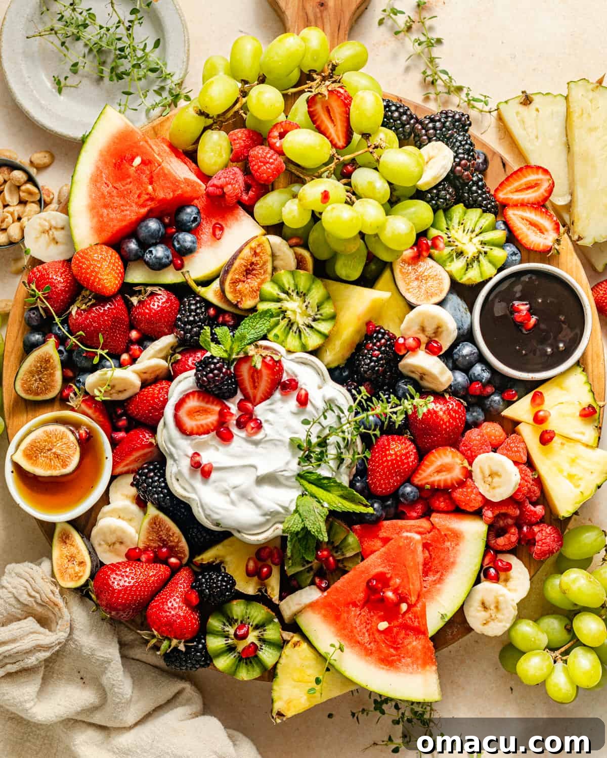 A beautifully arranged fruit platter with various fresh fruits and small bowls of dips, showcasing an enticing presentation.