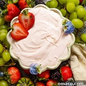 Cream cheese fruit dip in a bowl surrounded by grapes, strawberries, and blackberries.