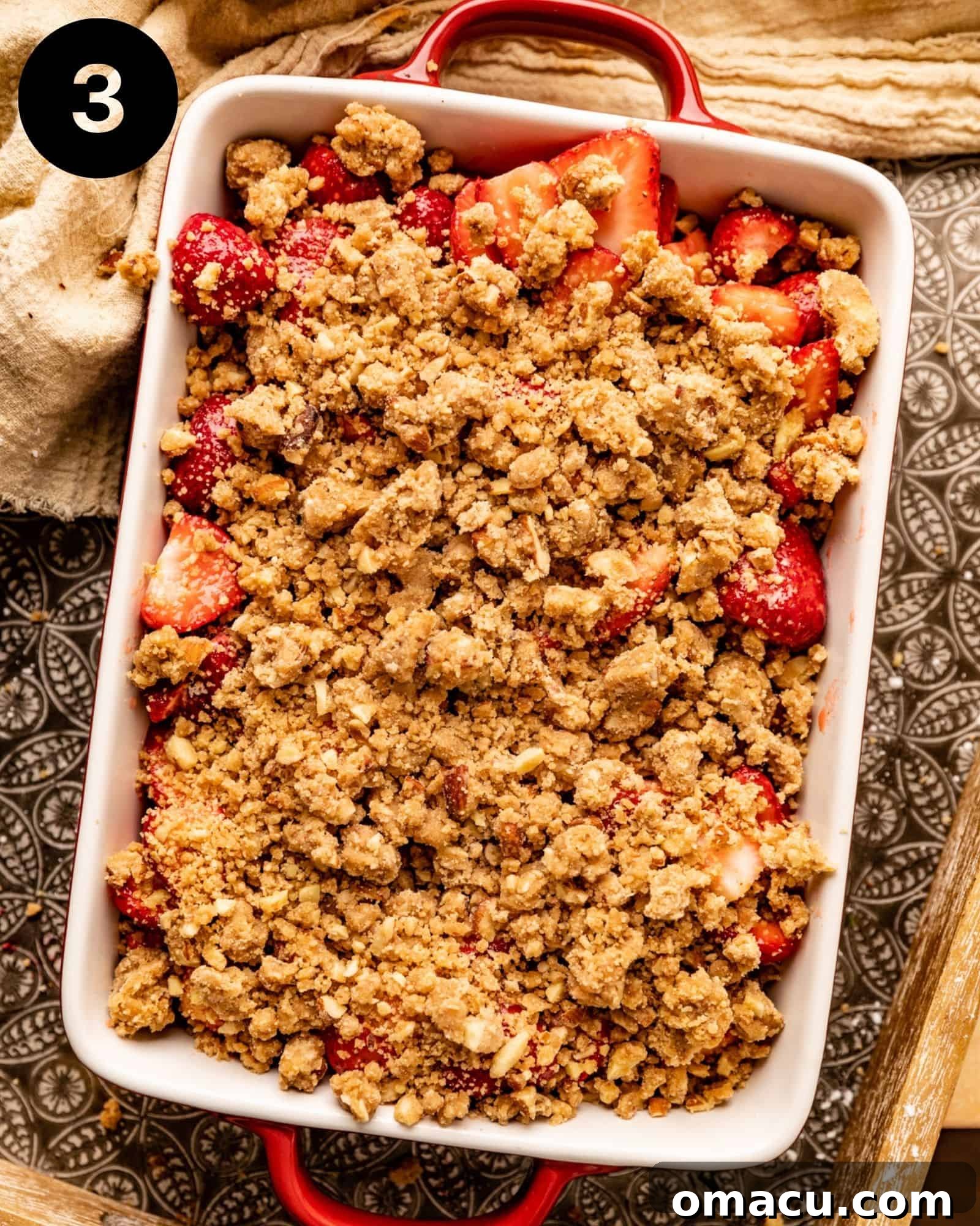 Strawberry crisp assembled in a baking dish, with the crumble topping spread over the fruit.