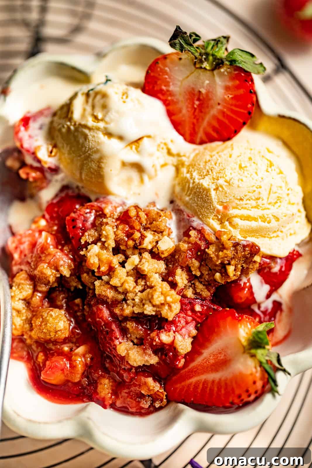 A close-up view of strawberry crumble in a bowl, highlighting the crunchy topping and juicy fruit.