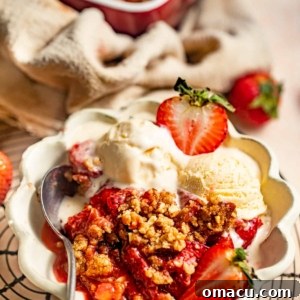 strawberry crumble in a bowl with a scoop of ice cream and fresh strawberries.