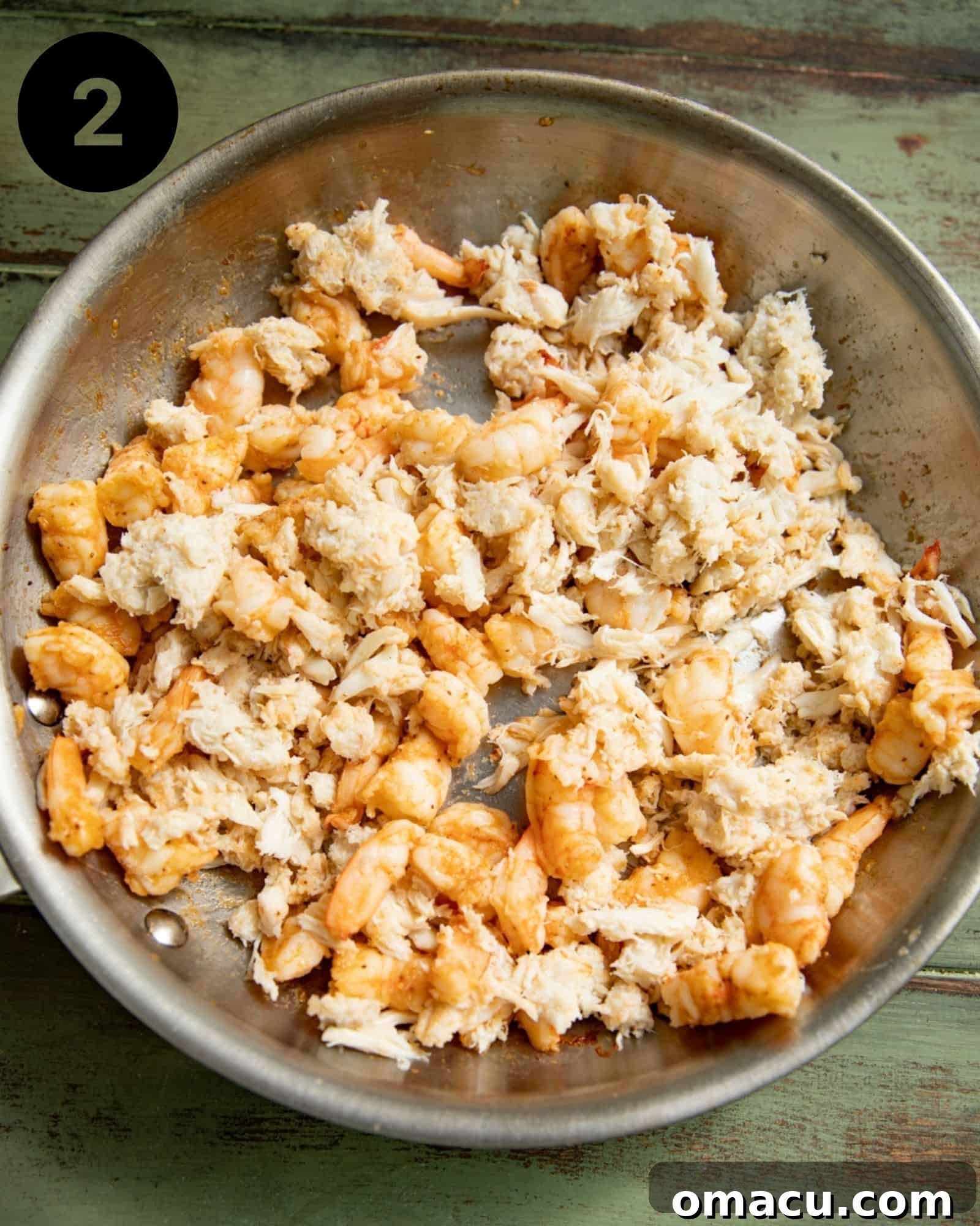 Shrimp and crab meat being gently tossed in a skillet, absorbing the flavors.