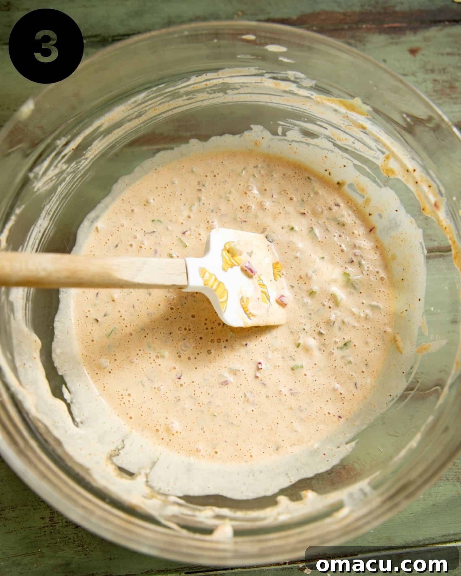 A large mixing bowl filled with the creamy, homemade dressing for seafood salad, ready to be combined with the other ingredients.